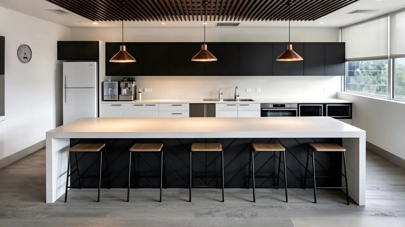 In the center is a long white waterfall-edge kitchen island with five modern black and wood bar stools lined up underneath. The island's base is dark with a chevron-patterned wood panel.