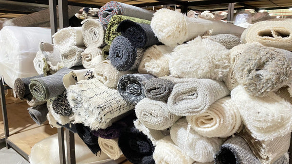 Rolls of textured fabric in various colors stacked on a rack.
