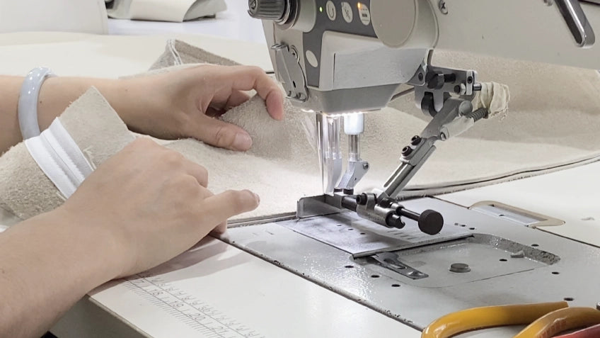 Person operating a sewing machine with a focus on hands and machine.