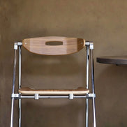 Puwabi X6198 architectural folding contract dining chair with wooden frame and fabric seat, displayed in a modern setting.