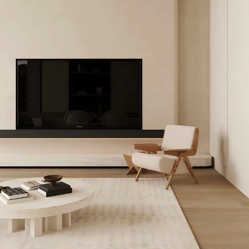 Modern living room with a large flat-screen TV mounted on the wall, a white armchair, and a coffee table.