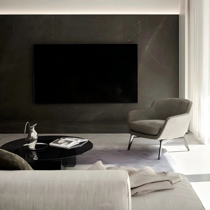 Modern living room with a gray armchair, coffee table, and television on a dark wall.